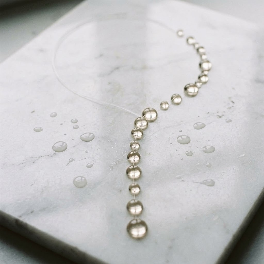 Dewdrop necklace styled with a white V-neck outfit in daylight